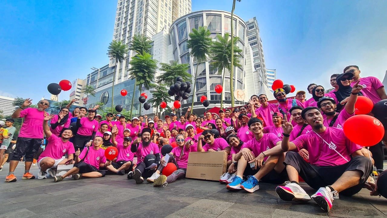 A large group of Oudpro community participants in matching shirts posing outdoors in front of a city venue.