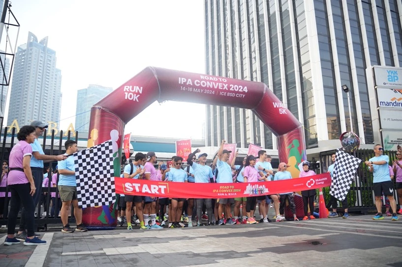 Hundreds of runners crossing beneath an event start and finish arch.