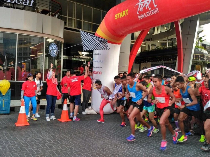Runners gathered beneath a red race start arch.