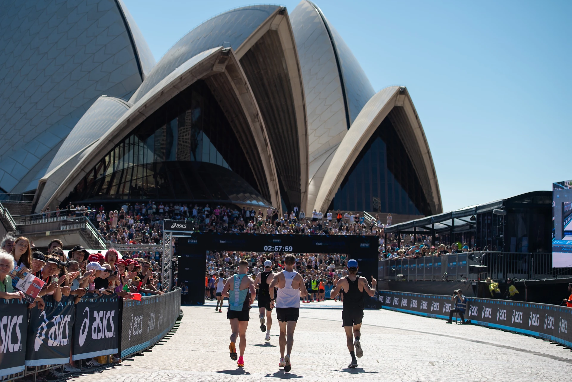Marathon runners on the Sydney course beside the Sydney Opera House and race grandstand.